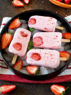 Creamy Strawberry Popsicles in a tray garnished with strawberries